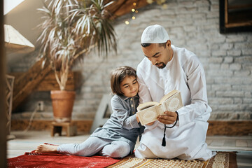 Middle Eastern father reads Koran to his daughter at home. © Drazen