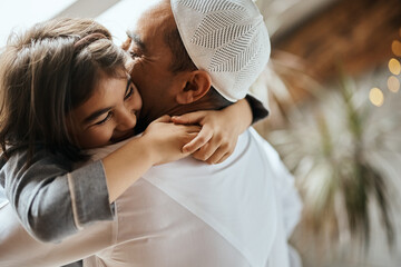 Happy Muslim father and daughter embrace at home.