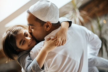Affectionate Middle eastern father kisses his small daughter at home.