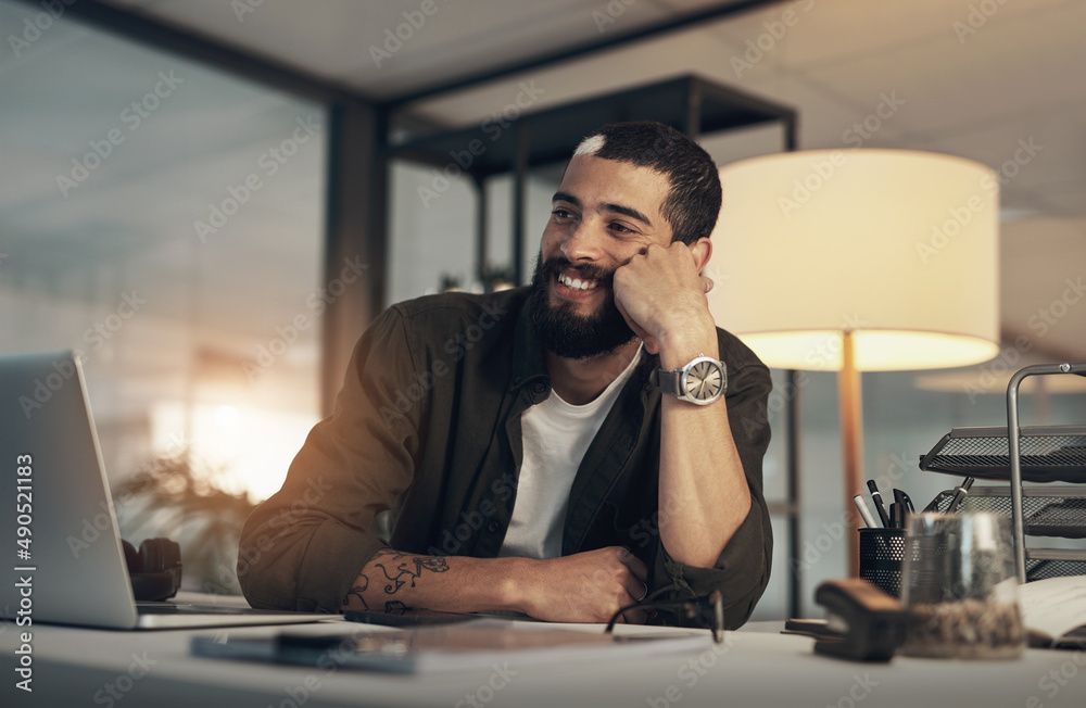 Poster the afterglow of getting everything done. shot of a young businessman using a laptop during a late n