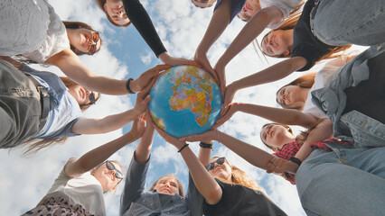 Earth conservation concept. 11 girls hug the earth globe with their hands. - obrazy, fototapety, plakaty