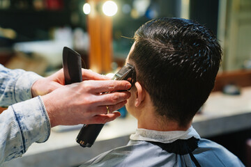 rear view. hairdresser makes haircut for man with hair clipper in barbershop