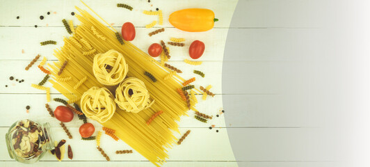 Raw pasta of various types and spices on a wooden table