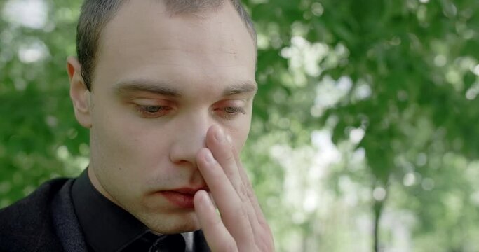 Sad young man cries on the cemetery. Funeral and farewell, honoring the passed relatives, 4k 60p Prores