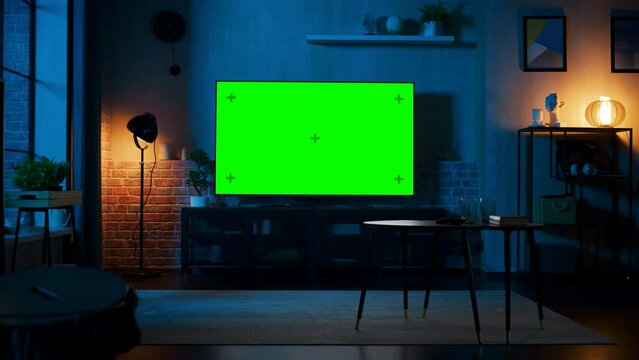 Stylish Loft Apartment Interior with TV Set with Green Screen Mock Up Display Standing on Television Stand. Empty Living Room at Home with Chroma Key Placeholder on Monitor. Panning Right Slider Shot.