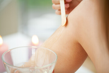 Obraz na płótnie Canvas Skin care, a woman applies wax to her leg to remove hair
