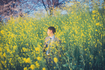 菜の花とスーツの男性