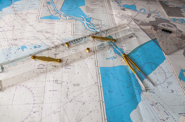 Maps of the ship for plotting. Plotter, divider and ruler. Close-up. - obrazy, fototapety, plakaty