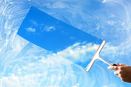 Washing of window with detergent and squeegee against blue sky