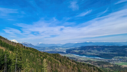 Scenic view on the Drava river in the Rosental valley on the way to Sinacher Gupf in Carinthia, Austria. Forest in early spring. The Hohe Tauern mountain range can be seen in the back. Sunny day. Hike