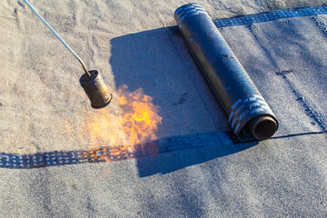 spring repair of a soft roof with rolled materials using a gas burner, the front and background are...