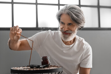 Mature man with incense sticks at home