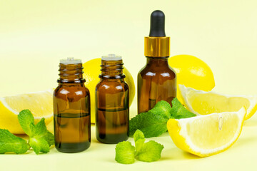 Essential oil of fragrant lemon and peppermint (mint) in dark brown glass bottles with a yellow background. Aromatherapy (anti-fatigue, relaxation), spa, skin care.