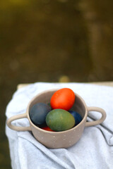 Ceramic bowl filled with painted Easter egss in jewel tones. Selective focus.