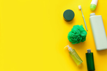Different cosmetic products, toothbrush and bath sponge on yellow background