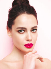 Fashion beauty portrait of young brunette woman with evening stylish  makeup and perfect clean skin. Sexy model with hair in a bun posing in studio near white wall. With pink bright natural lips