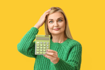 Beautiful woman with calculator on yellow background