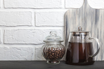Glass coffee pot with hot coffee drink and coffee beans in a jar on a kitchen countertop. Food...