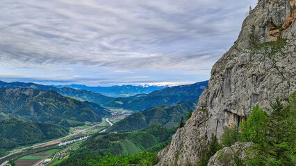 A rock formation with scenic view from mount Roethelstein near Mixnitz in Styria, Austria. Landscape of green alpine meadow and a small village in the valley of Grazer Bergland in Styria, Austria