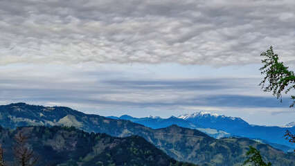Panoramic view on the Eisenerzer Alps from below mount Roethelstein near Mixnitz in Styria, Austria. Snow capped mountain of the Ennstal Alps beyond the Grazer Bergland in Styria, Austria. Overcast