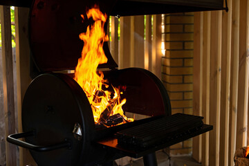 Obraz premium Hot empty charcoal barbecue grill with bright flame. Summer vacation with friends. Soft selective focus.