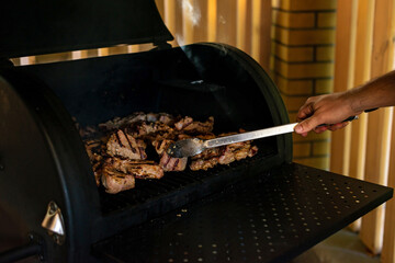Juicy cuts of beef and pork meat on an open grill. Summer vacation barbecue with friends. Soft selective focus.