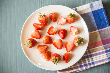Strawberries cut in half and put several pieces on a plate on the ground.