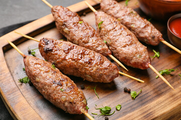 Wooden board of skewers with tasty lula kebab on table, closeup