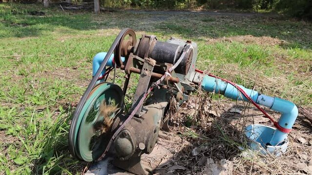 Lift pump underground water. An old hoist pump is pumping artesian wells with a motor and belt from solar energy in a rural farm.