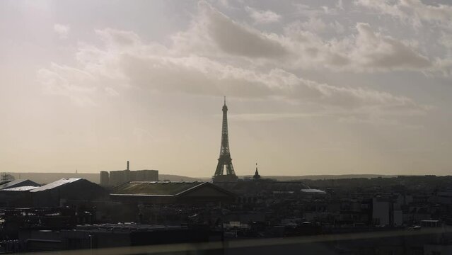View of Eiffel tower with sun light beams over paris rooftops Slow Motion 4k 30p