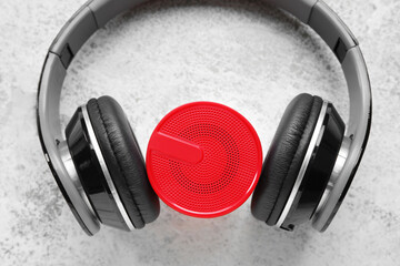 Headphones and wireless portable speaker on grunge background