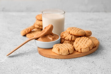 Wooden board with tasty peanut cookies on light background