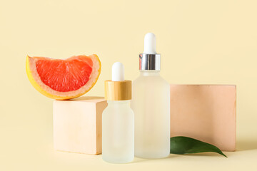 Composition with bottles of essential oil, grapefruit slice and decor on color background