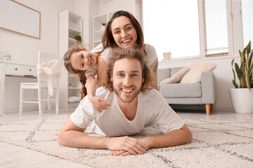 Happy young family lying on carpet at home