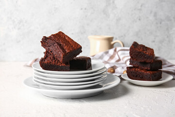 Plates with pieces of delicious chocolate brownie on light background