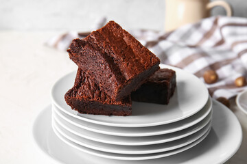 Plates with pieces of delicious chocolate brownie on light background