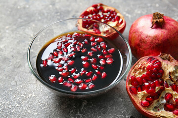 Bowl of pomegranate molasses and fresh fruits on grey background