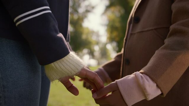 Parent hands letting go child arm green park closeup. Emotional separation issue