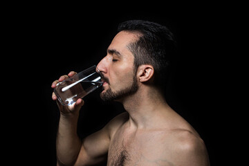 A man drinks water on a black background. Pure drinking water. Thirst quencher