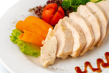 Pieces of boiled chicken breast with vegetables over white background