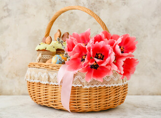 Fototapeta na wymiar Gift basket with tulip flowers on light background