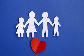 Happy paper cut family holding hands on blue background with red heart.