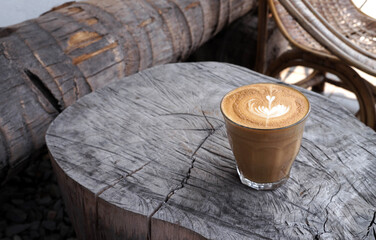 Close-up hot coffee in cup with heart shape latte art on dark brown old wood table at caff food and drink concept.