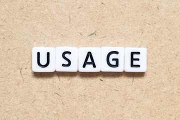 White tile alphabet letter with word usage on wood background