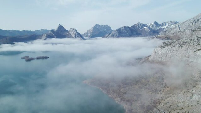 Drone camera flyng towards a mist cloud above a lake in Le&oacute;n, Spain. Mountain range background. Plain daylight. 