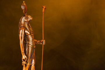 metal golden statue of the Egyptian sun god Ra on a black background with smoke - obrazy, fototapety, plakaty