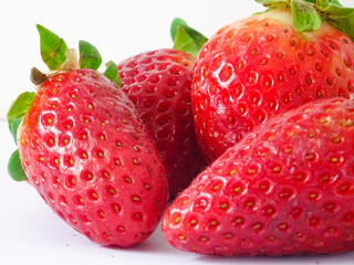 Closeup of a group of fresh strawberries with leaves isolated over a white background