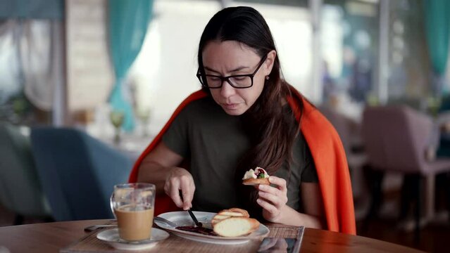 woman is eating bread with pate in restaurant during lunch, female visitor of restaurant