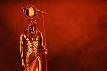 metal golden statue of the Egyptian sun god Ra on a black background with smoke