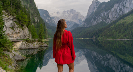 Naklejka premium Beautiful girl in a red dress in the mountains near the lake